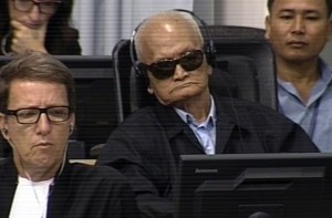 Nuon Chea and his defense team watch the prosecution's closing statements.